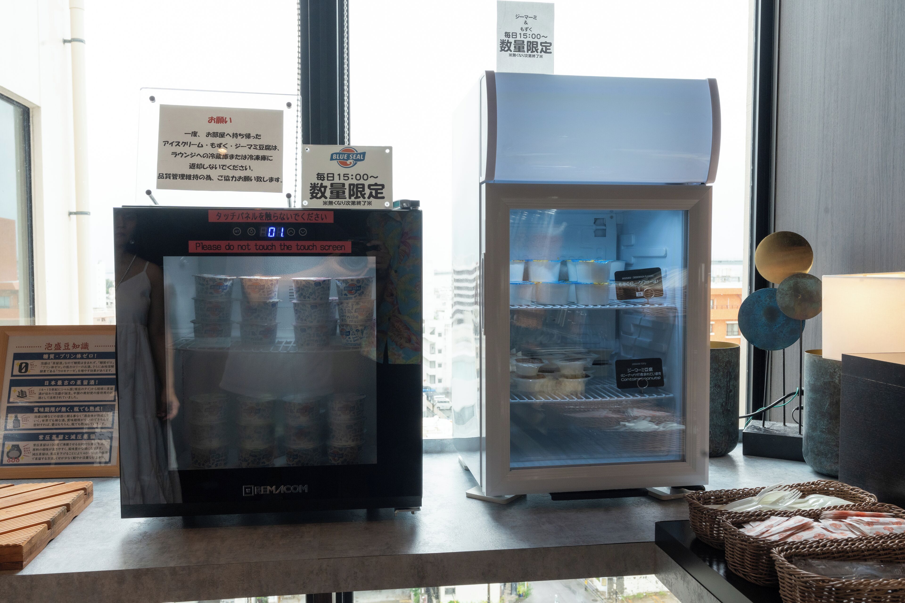 Une machine distributrice et un réfrigérateur se trouvent dans une pièce dotée d’une fenêtre.