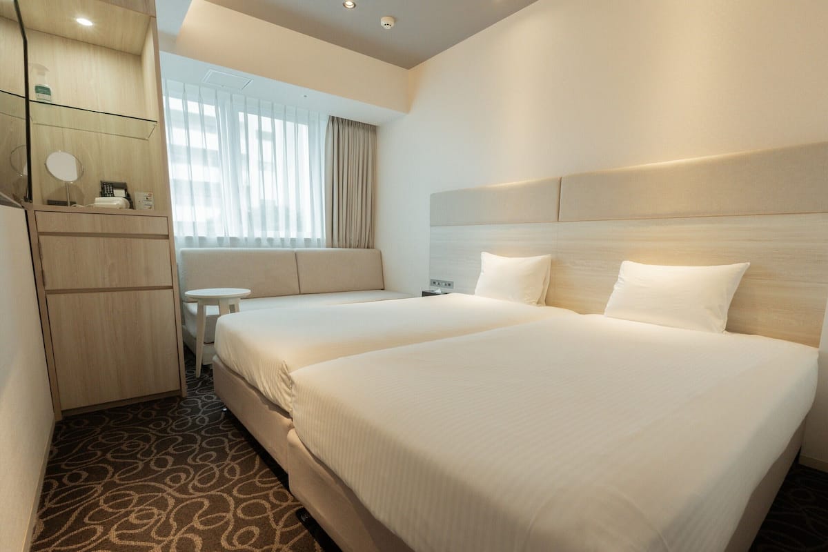 Habitació d'hotel amb un llit gran, un sofà, una taula petita i una nevera minibar.