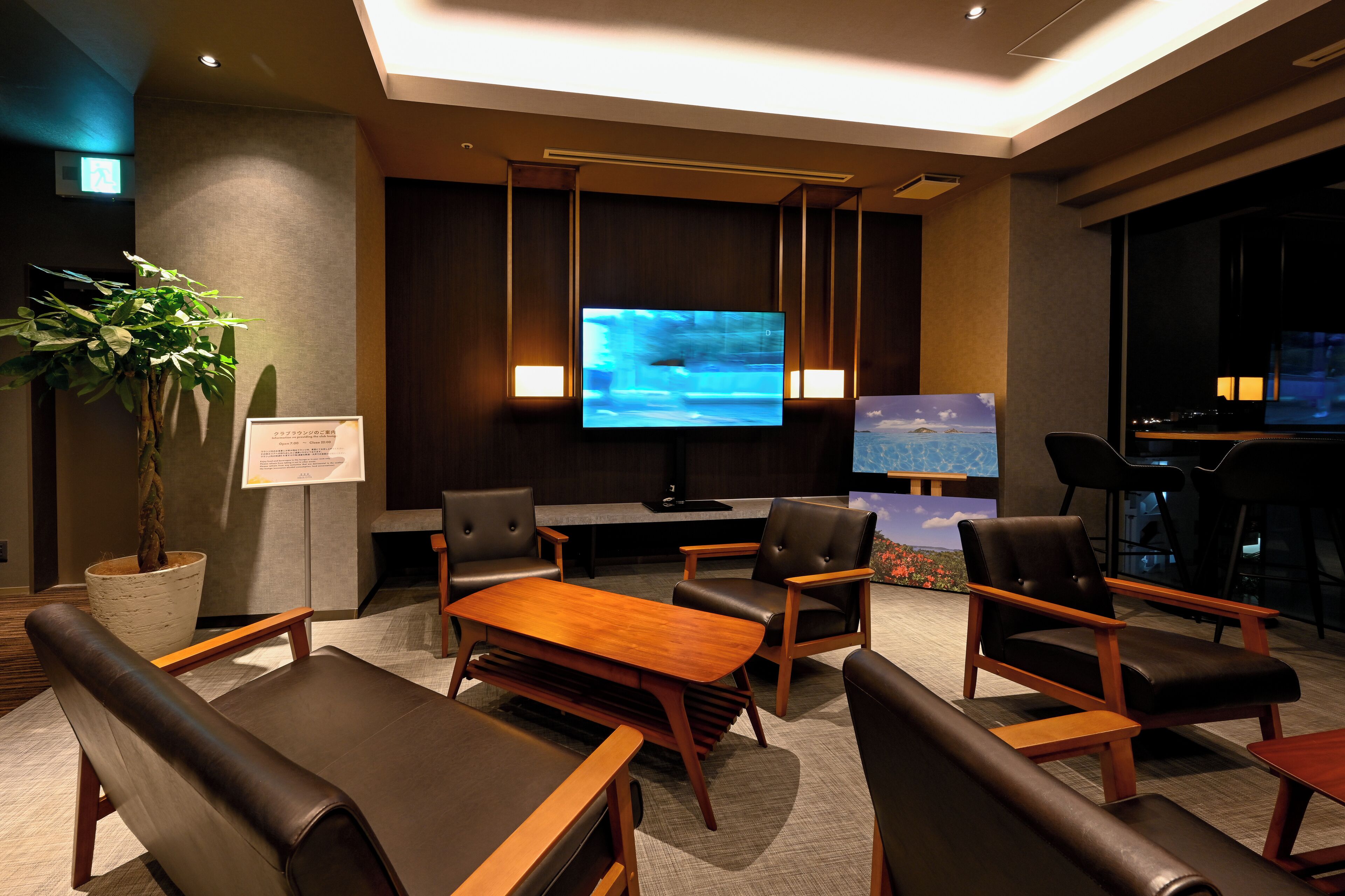 A conference room with a large screen, seating, and a plant.
