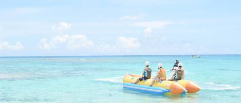 A group of people on a yellow and blue inflatable raft in clear turquoise water.