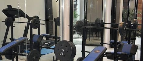 A gym with weightlifting equipment and exercise benches.