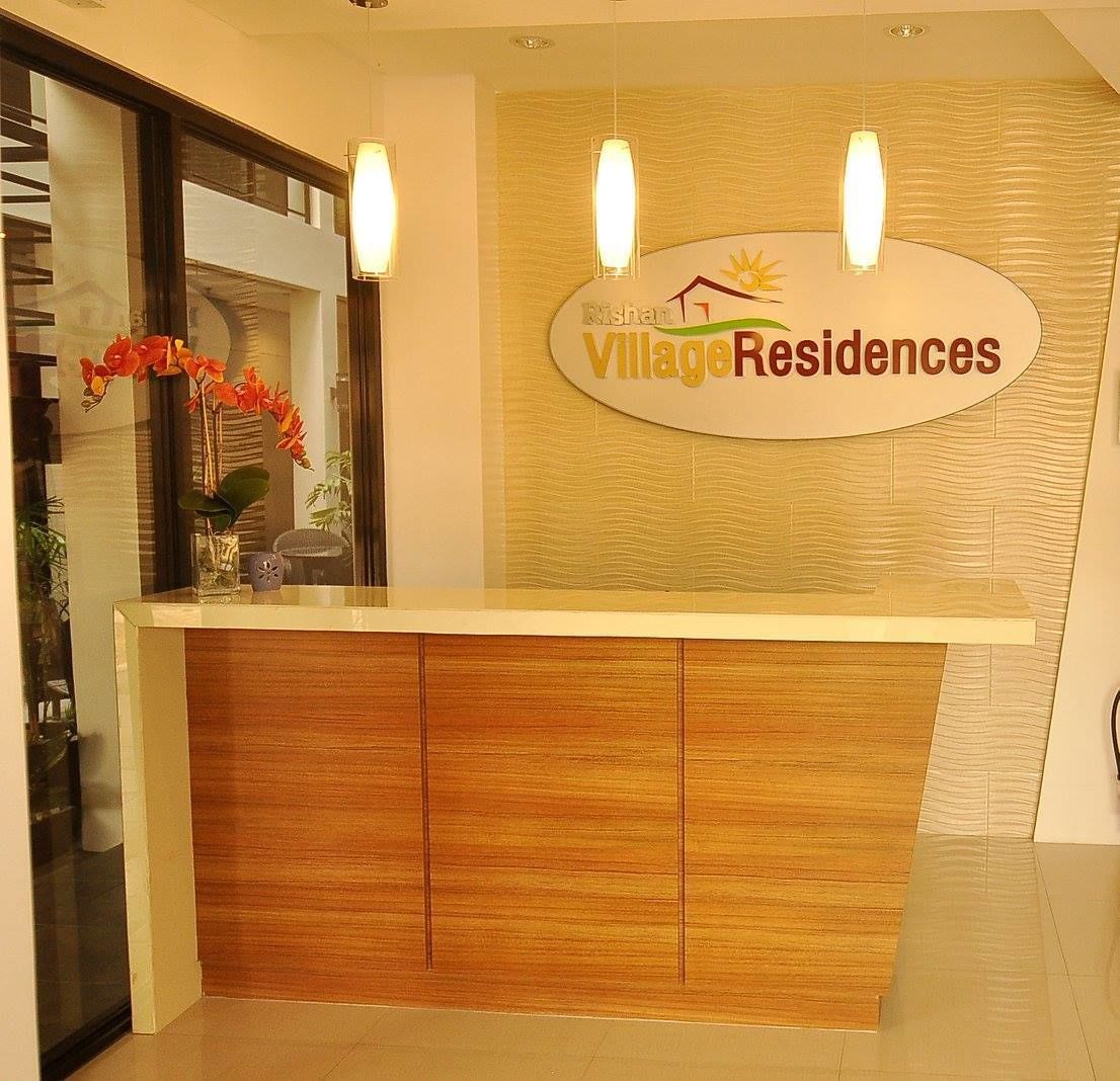 A reception desk with a sign reading "Rishan Village Residences".