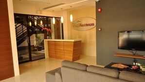 A modern living room with a grey sofa, a wooden cabinet, a flat-screen TV, and a staircase leading to another level. - Rishan Village Residences (Angeles City)