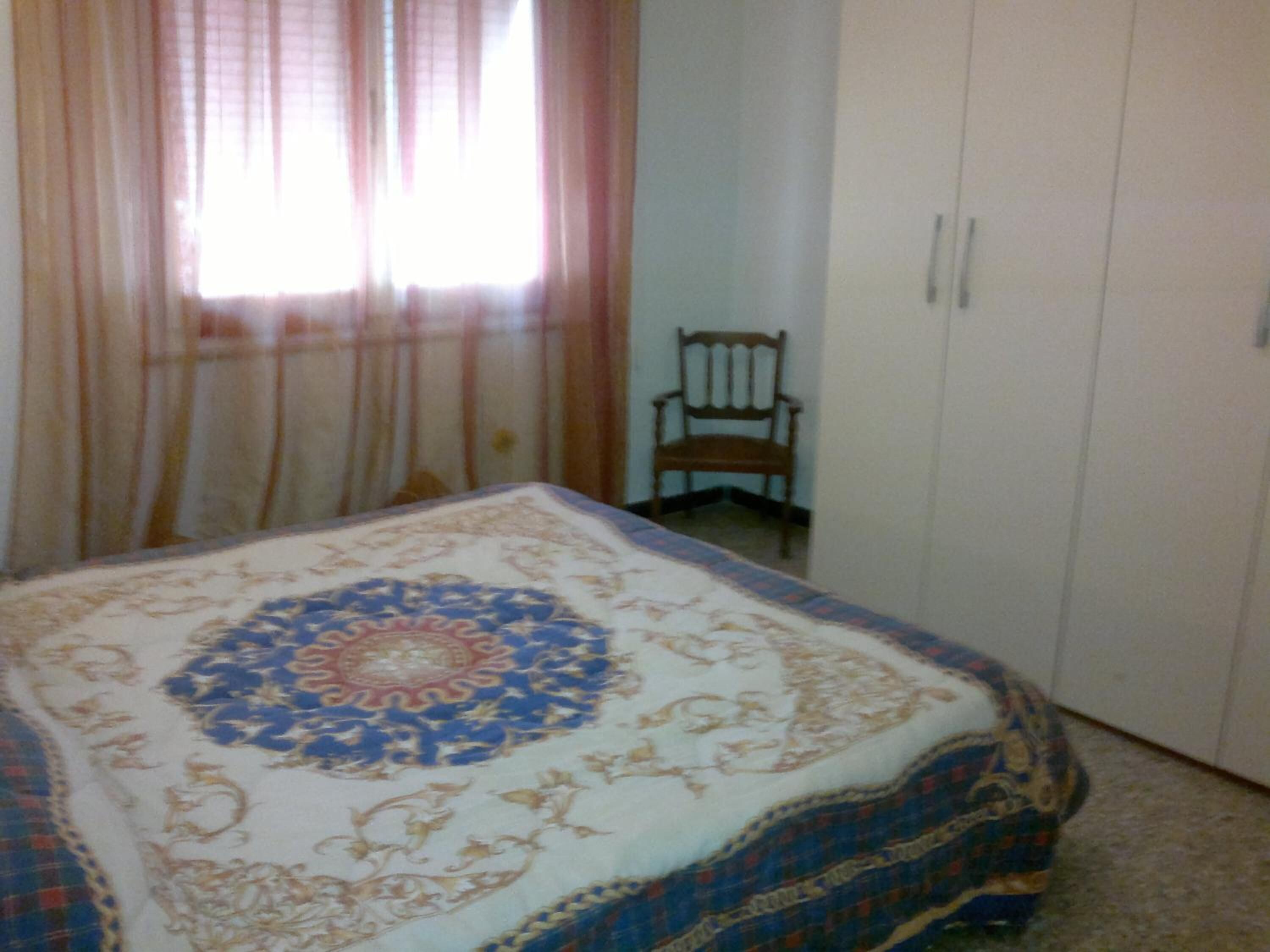 Una camera da letto con un letto, una sedia e un armadio.