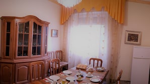 A dining area with a wooden cabinet, dining table set with plates, cups, and a tray of bread. - B&B In Centro (San Benedetto del Tronto)
