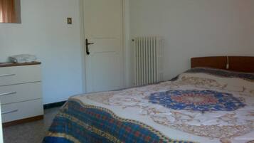 Un dormitorio con cama, cómoda, radiador y puerta.