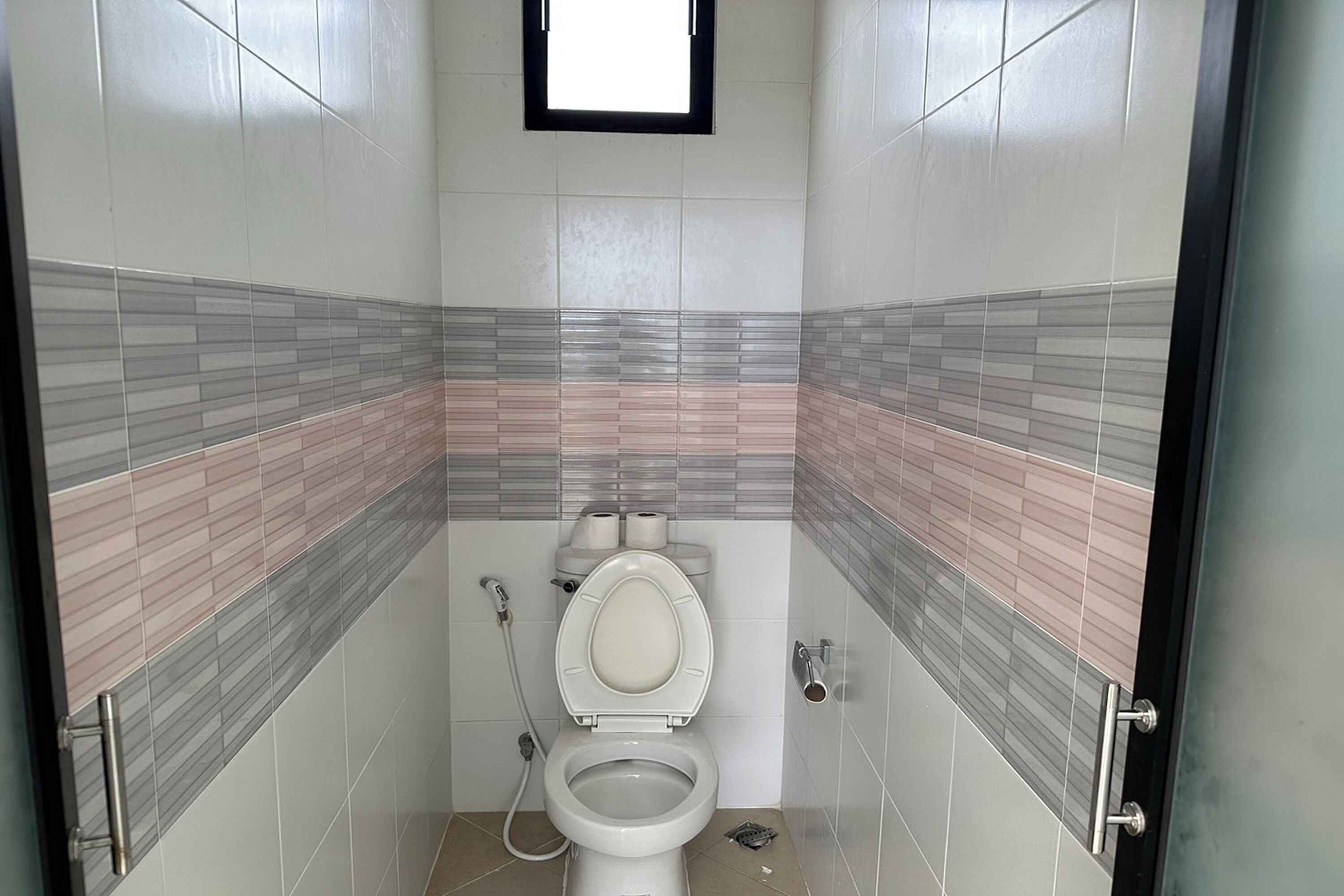 Un baño pequeño con azulejos, un inodoro, una ducha y una ventana.