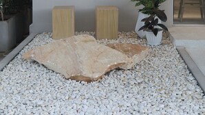 A modern interior with a stone floor, wooden stools, and a potted plant.