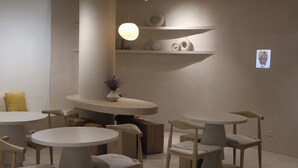 A modern interior with round tables and chairs, a central light fixture, and decorative shelves.