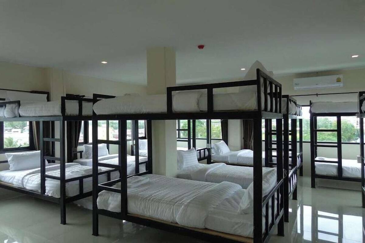 A room with bunk beds, large windows, and an air conditioning unit.