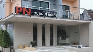 A boutique house with a modern design, featuring a prominent 'PN Boutique House' sign, a balcony with seating, and a well-maintained entrance area with potted plants and decorative stones.