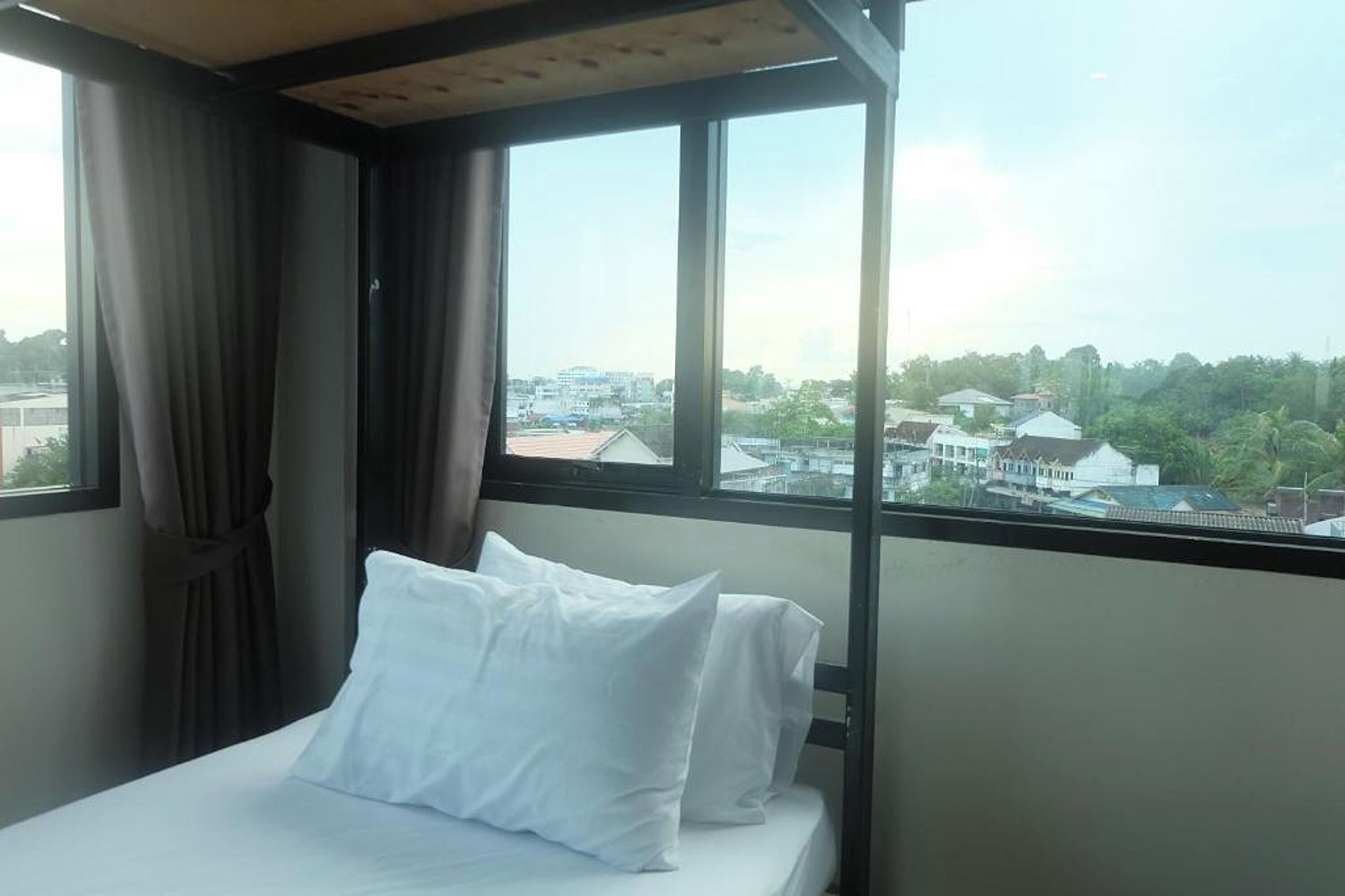 Une chambre à coucher avec un lit, des rideaux et une grande fenêtre donnant sur la ville.