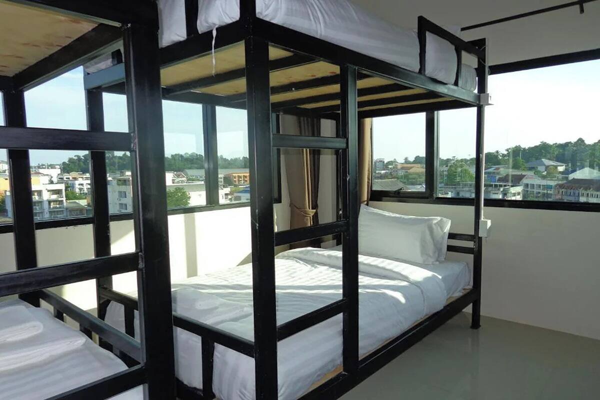 A bunk bed room with a city view, large windows, and a curtain.