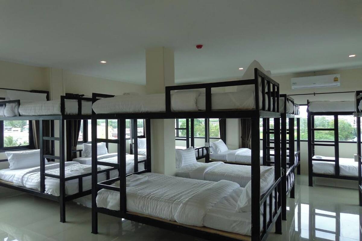 A hotel room with bunk beds, large windows, and an air conditioning unit.
