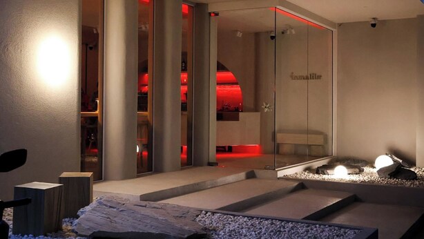 A modern interior with a glass partition, a reception area, and a seating area with a small water feature.