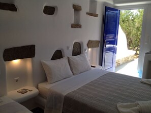A bedroom with a bed, a nightstand, and a blue door leading outside. - Stavroula Studios (Mykonos)