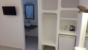A compact bathroom with a sink, mirror, and shower area. - Stavroula Studios (Mykonos)