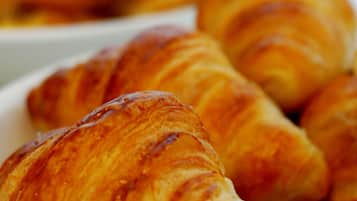 Gros plan sur des croissants dorés et bruns disposés sur une assiette blanche.