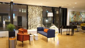 Un vestíbulo moderno con un sofá azul, un sillón naranja y un piano.