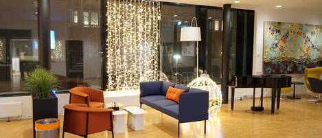 Un vestíbulo moderno con un sofá azul, un sillón naranja y un piano.