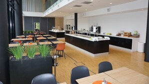 Un comedor moderno con varias mesas y sillas, una isla central con un fregadero y una barandilla de cristal que da a todo el espacio.