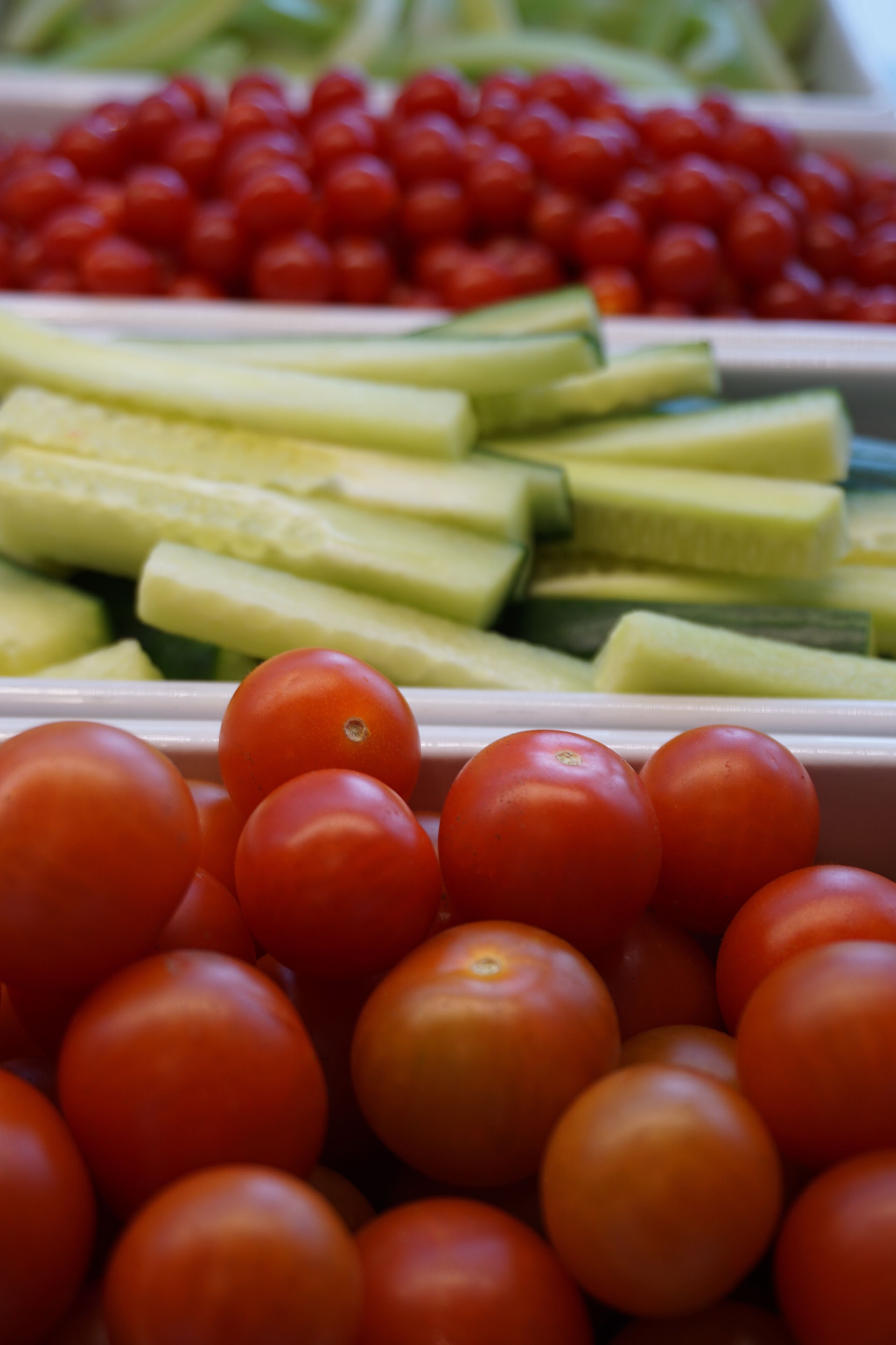 A display of fresh tomatoes and cucumbers in a market setting.