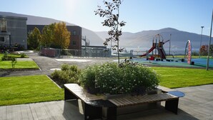 Un parque con un área de juegos, bancos y vistas a las montañas.