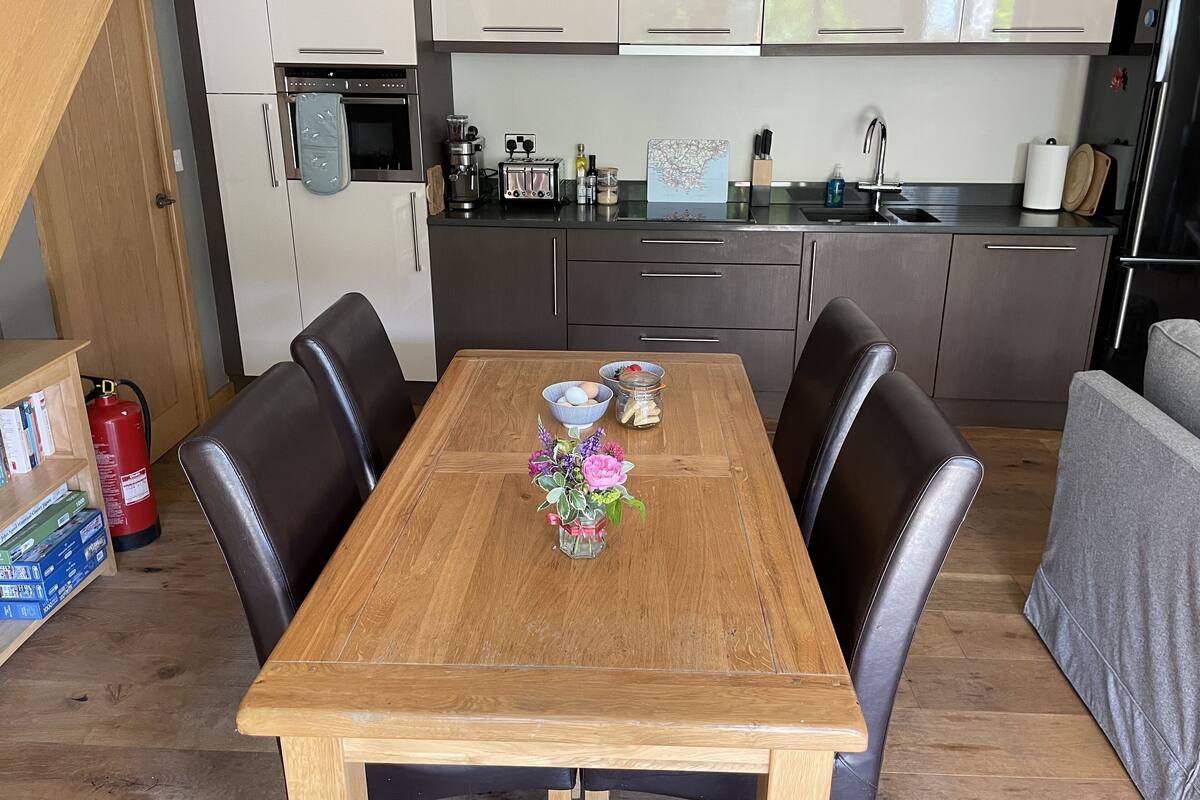 A compact kitchen with modern appliances, a dining table with chairs, and a small seating area.