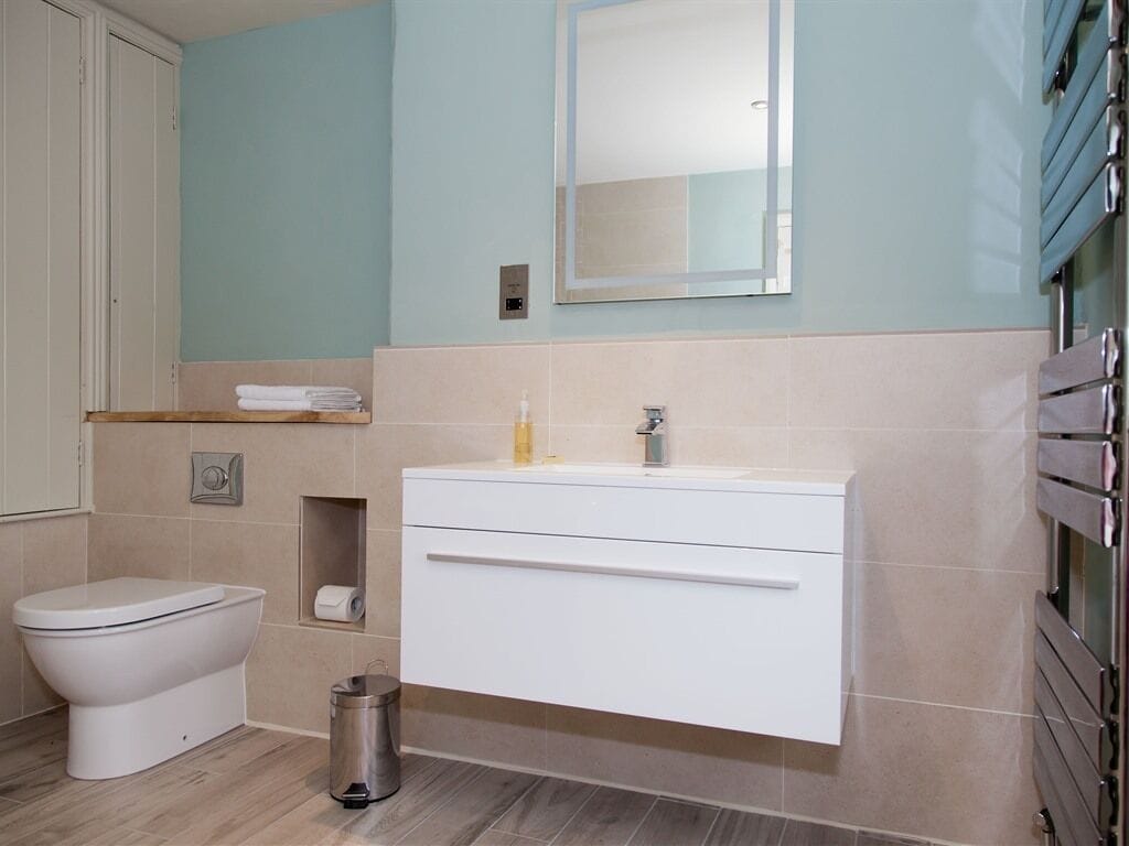 Un baño con inodoro, lavabo con espejo y cubo de basura.