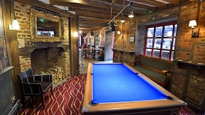 A billiards room with a pool table, a fireplace, and a brick wall. - The Royal Victoria & Bull Hotel (Dartford)
