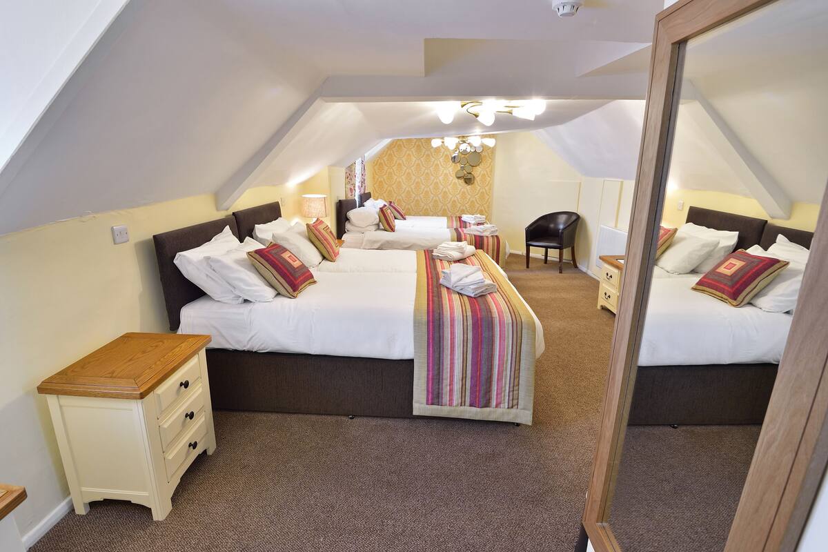 A bedroom with two beds, a nightstand, a chair, and a mirror.