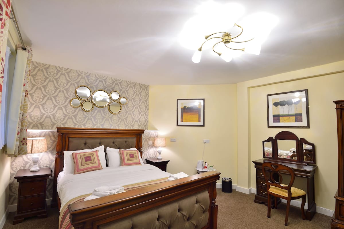 A neatly arranged bedroom with a bed, bedside tables, a dresser, and a desk.