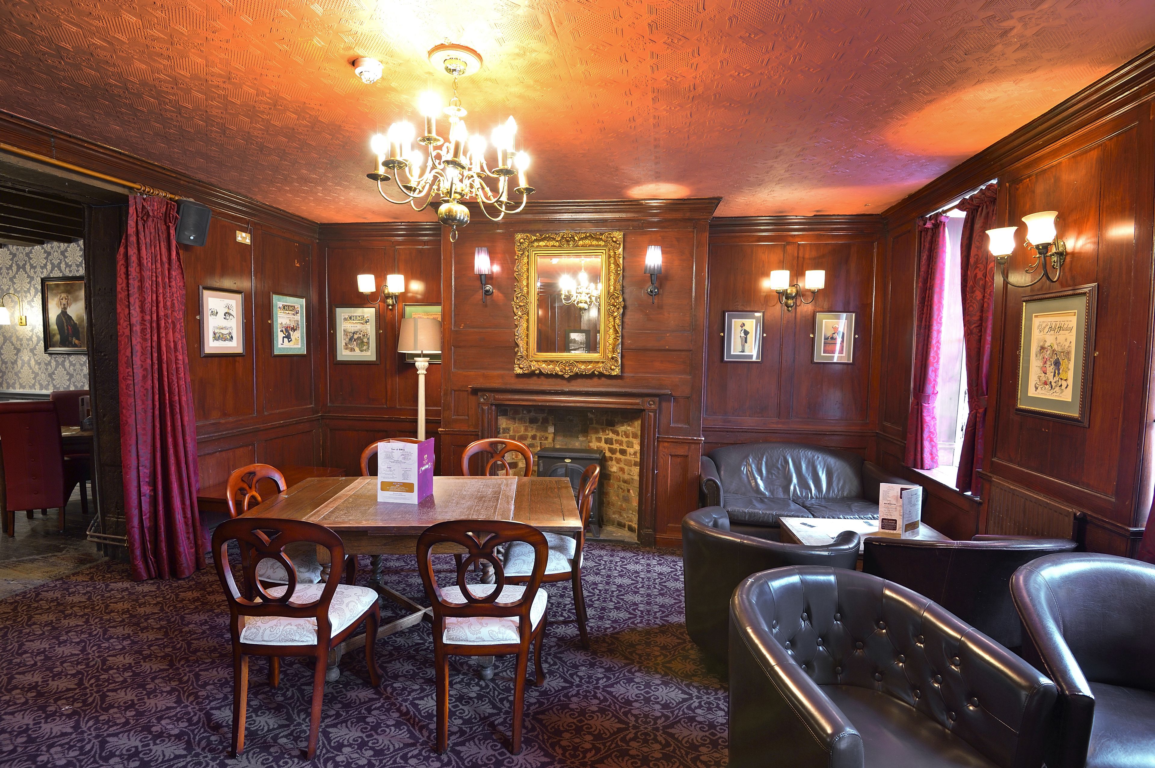 A formal room with a wooden table, chairs, a fireplace, and a chandelier.