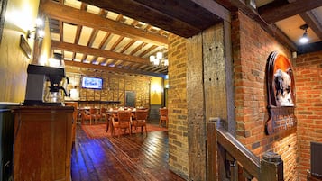 Un interior rústico con vigas de madera a la vista, paredes de ladrillo y una zona de bar de madera.