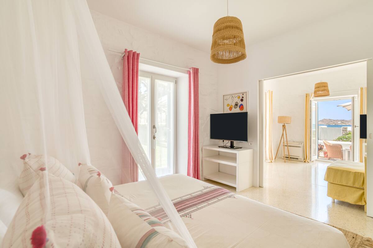 Un dormitorio con cama, televisor y ventana con cortinas.