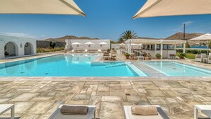 Zona de piscina amb gandules i ombrel·les, paviment de pedra i vistes a les muntanyes.
