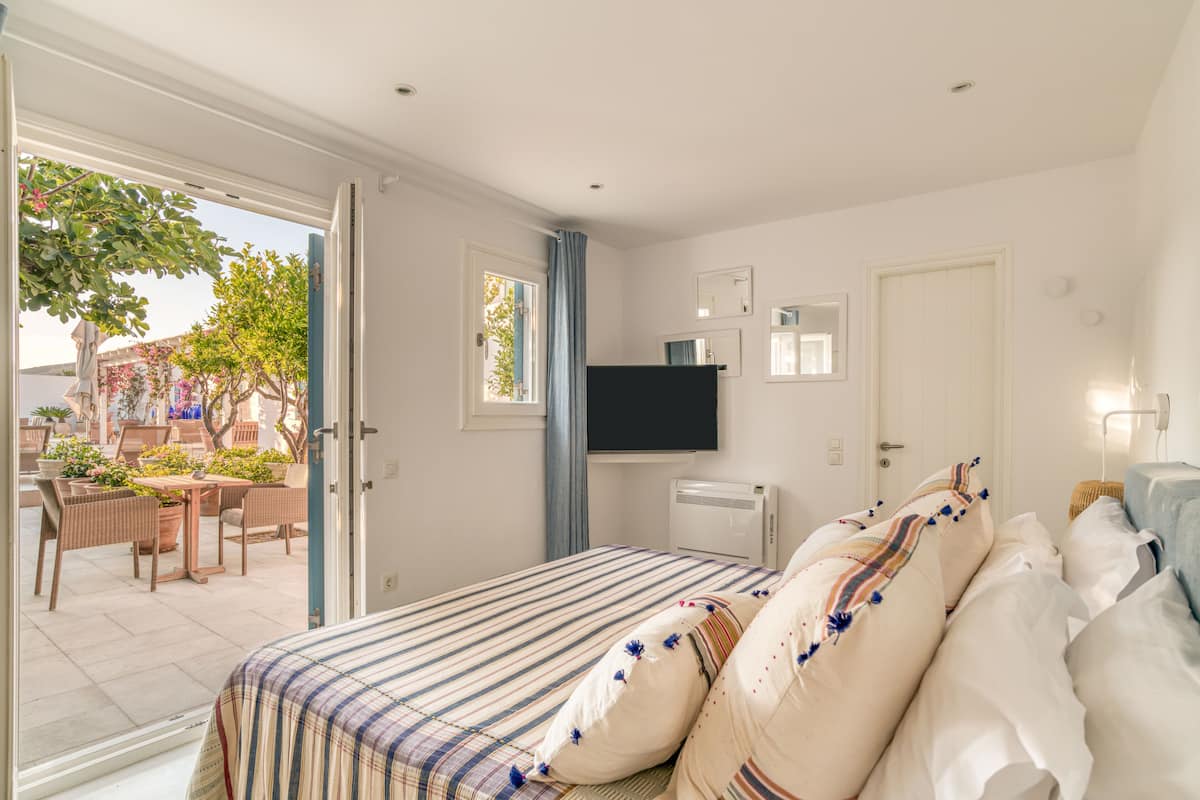 Un dormitorio con cama, televisor y ventana.