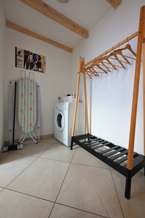 A laundry area with a washing machine, drying rack, and ironing board. - Hybernska Apartments (Prague)