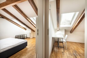 A bedroom with a bed, a desk with a chair, and skylights. - Hybernska Apartments (Prague)