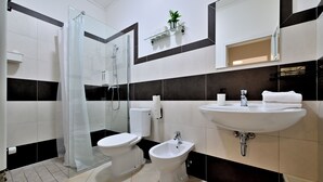 Un baño moderno con cabina de ducha de vidrio, inodoro, bidé y lavamanos.