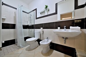 A modern bathroom with a glass shower enclosure, a toilet, a bidet, and a sink. - Hybernska Apartments (Prague)