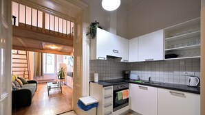 Una cocina moderna con armarios blancos, una encimera negra y un horno empotrado. Hay un cubo de basura y una planta en la encimera.