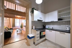 A modern kitchen with white cabinets, a black countertop, and a built-in oven. There is a trash bin and a plant on the counter. - Hybernska Apartments (Prague)