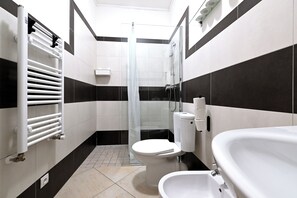 A modern bathroom with a toilet, bidet, and bathtub. - Hybernska Apartments (Prague)
