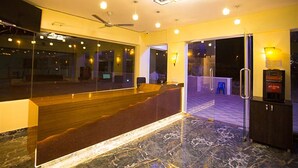 Un hall d’hôtel avec un sol en marbre, un espace salon, un grand miroir et un ventilateur de plafond.