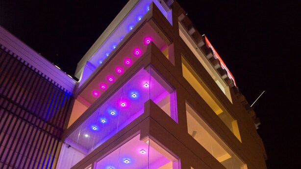Un bâtiment moderne à plusieurs étages, doté de grandes fenêtres et d’un éclairage LED aux couleurs vives.