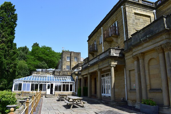 A historic building with a conservatory, outdoor seating, and classical architecture.