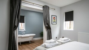 A modern bathroom with a bathtub, a sink, and a window. - Accommodation at Salomons Estate (Royal Tunbridge Wells)