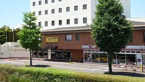Ein mehrstöckiges Hotel mit weißer Fassade, zahlreichen Fenstern und einem Schild, das einen Preis von 5.800 Yen anzeigt.