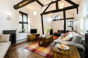 Una sala de estar acogedora con piso de madera, un sofá, una mesa de centro y un televisor.
